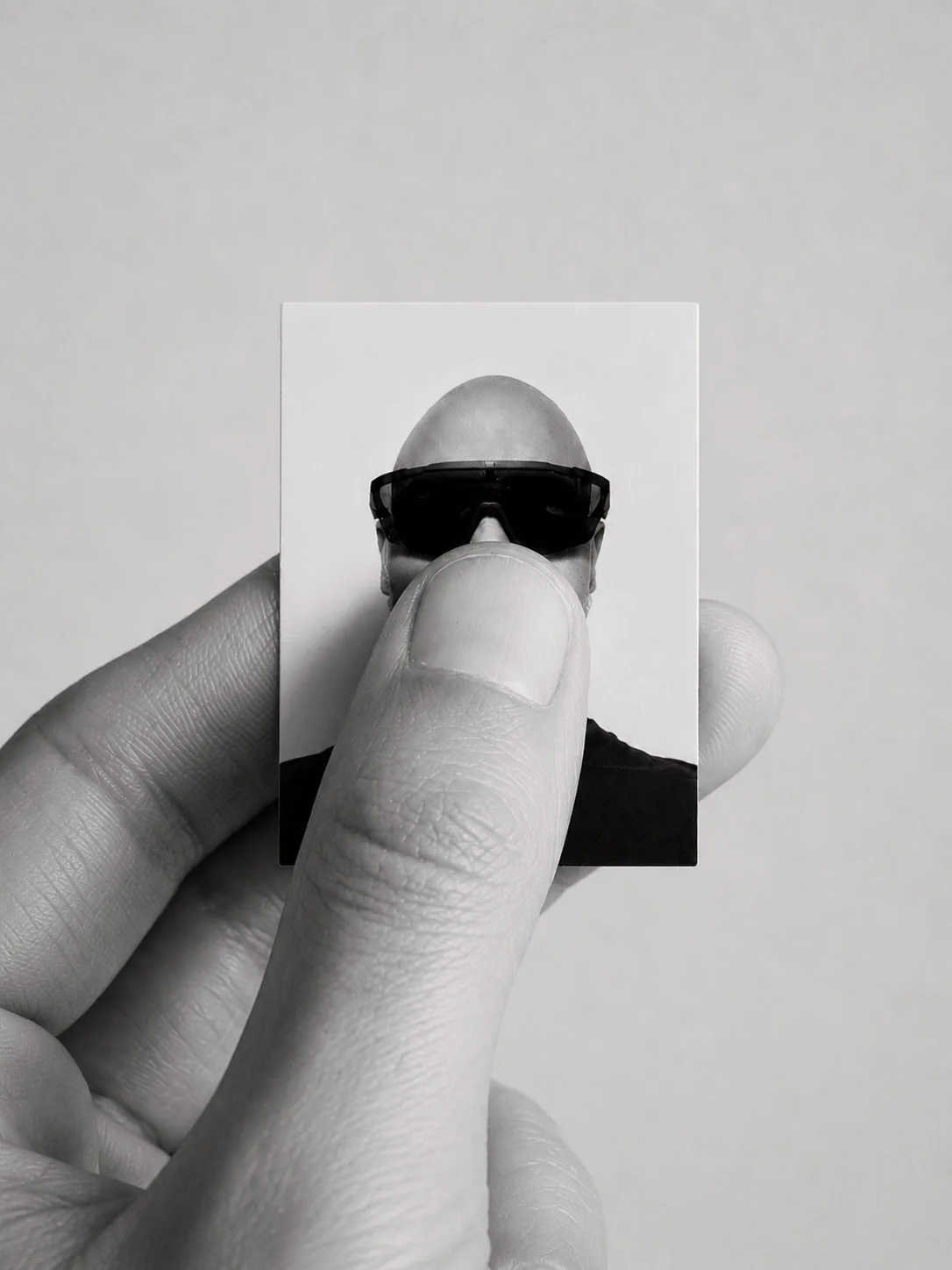 A hand holding a miniature monochrome portrait of the DigiHold founder